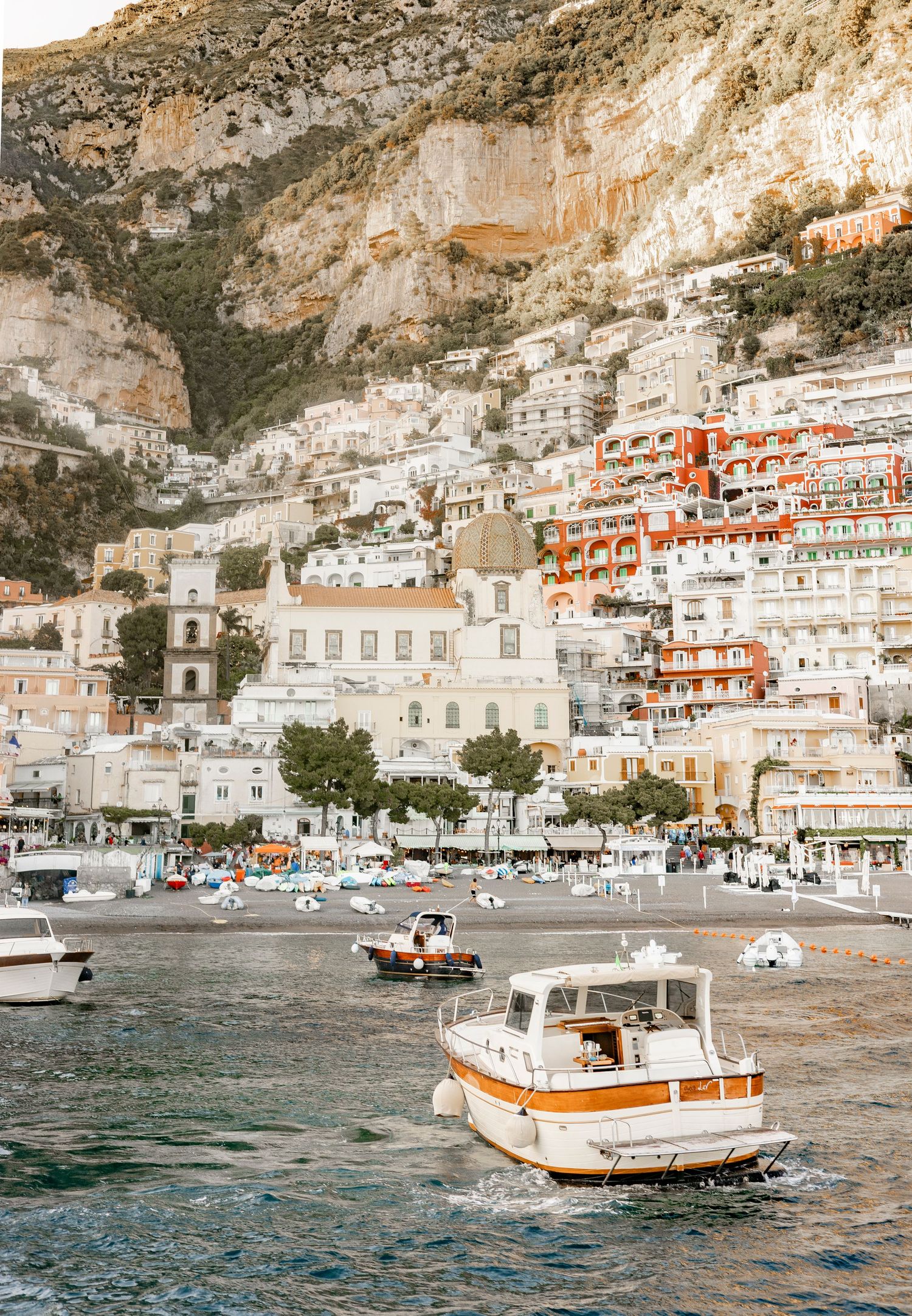 Colorful cliffside buildings of Positano overlook the Amalfi Coast harbor with boats.