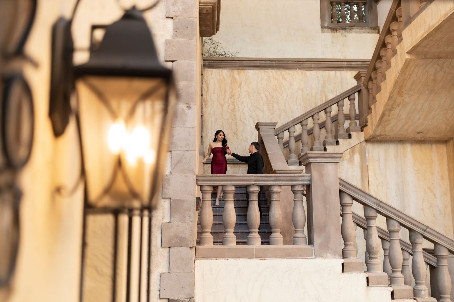 Couple holding hands on elegant marble staircase of a grand building.