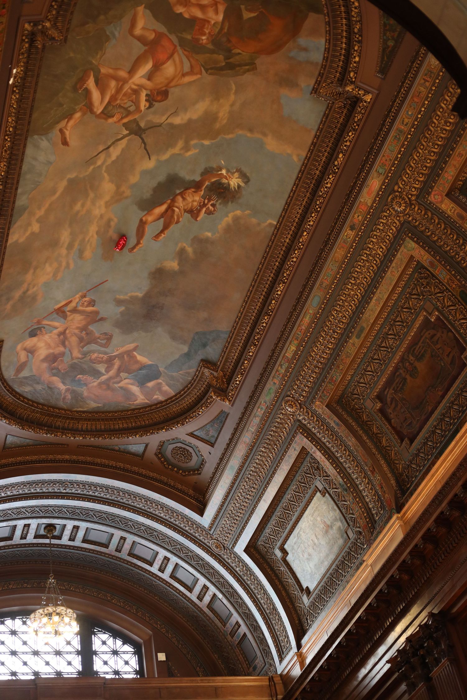 Ornate ceiling with classical baroque fresco paintings, gilded moldings, and arched architectural details in a grand historic building.