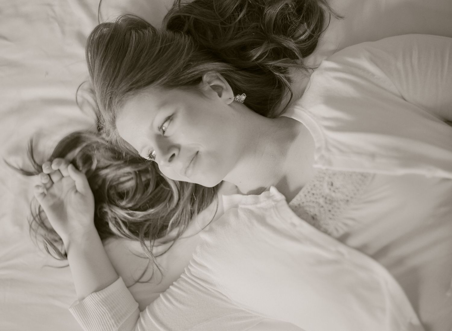 Soft black and white portrait showing someone resting peacefully on white bedding.