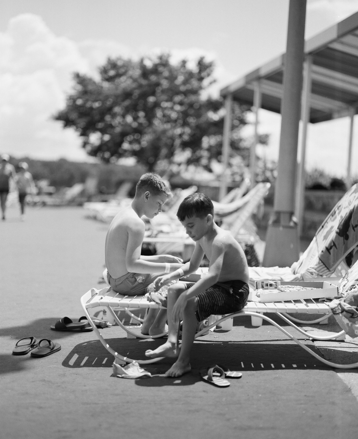 People lounging on deck chairs in a black and white seaside scene.