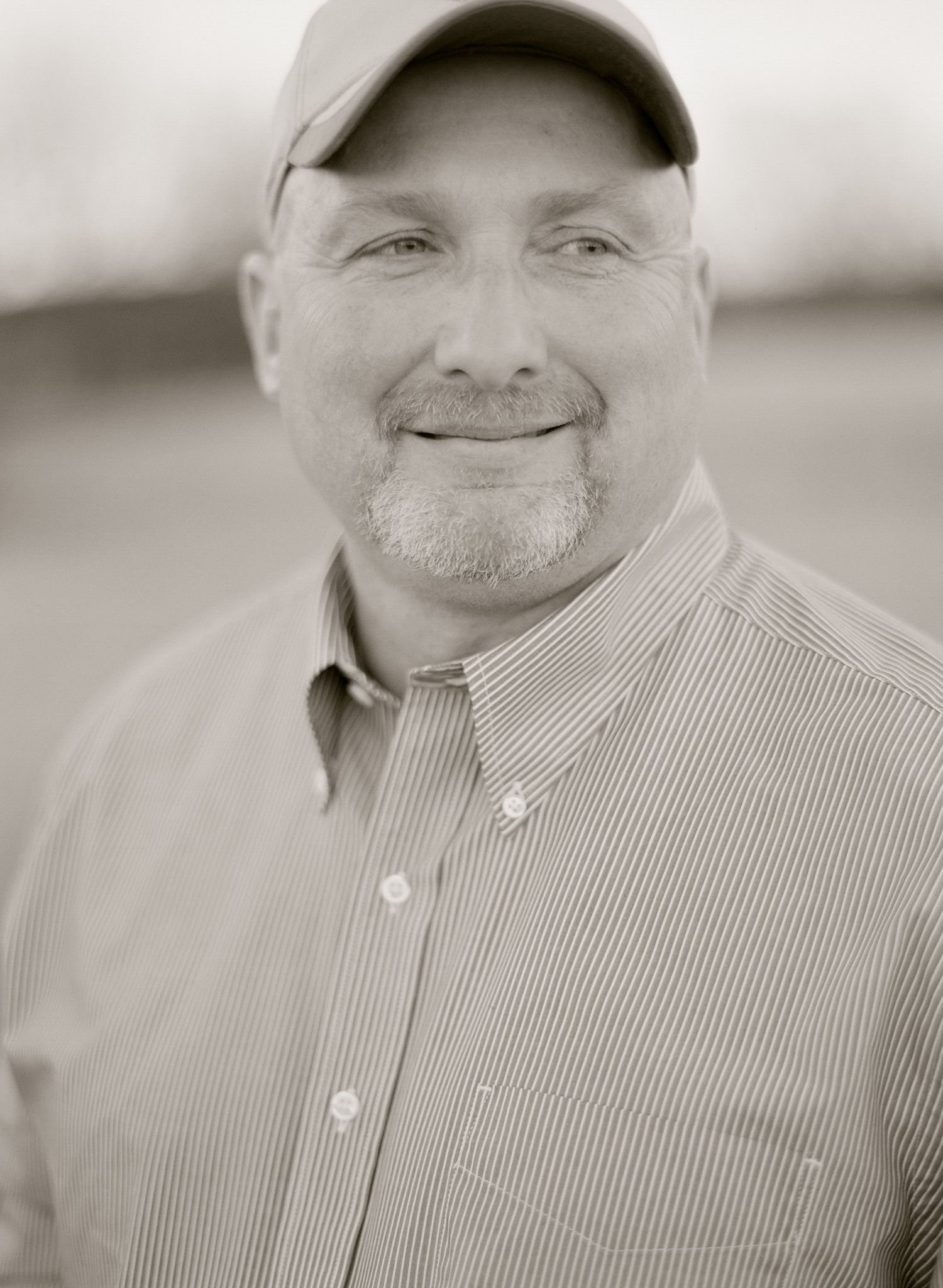 Black and white portrait showing warm smile against neutral background.
