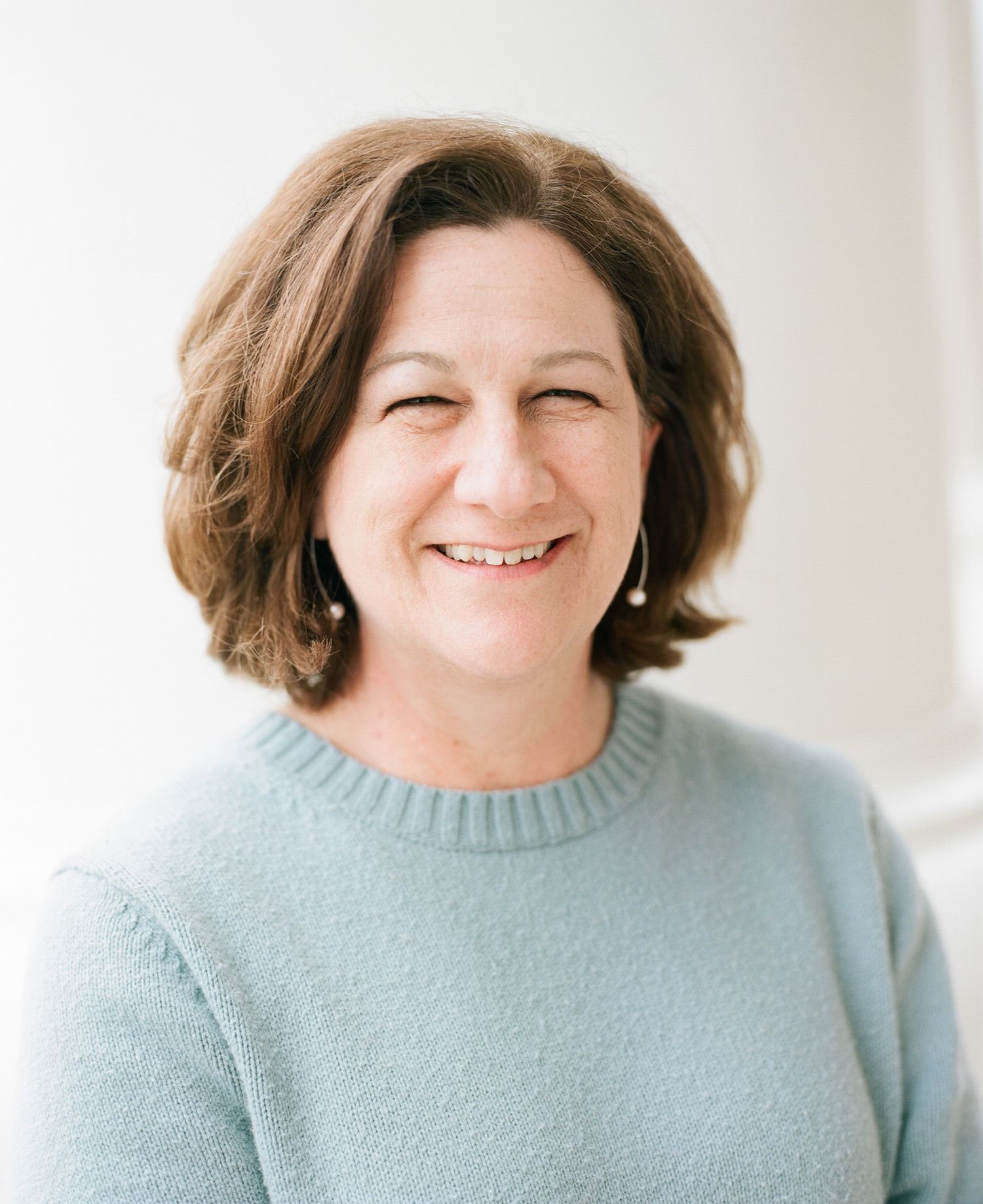 Portrait of someone wearing a soft blue sweater against a white background.