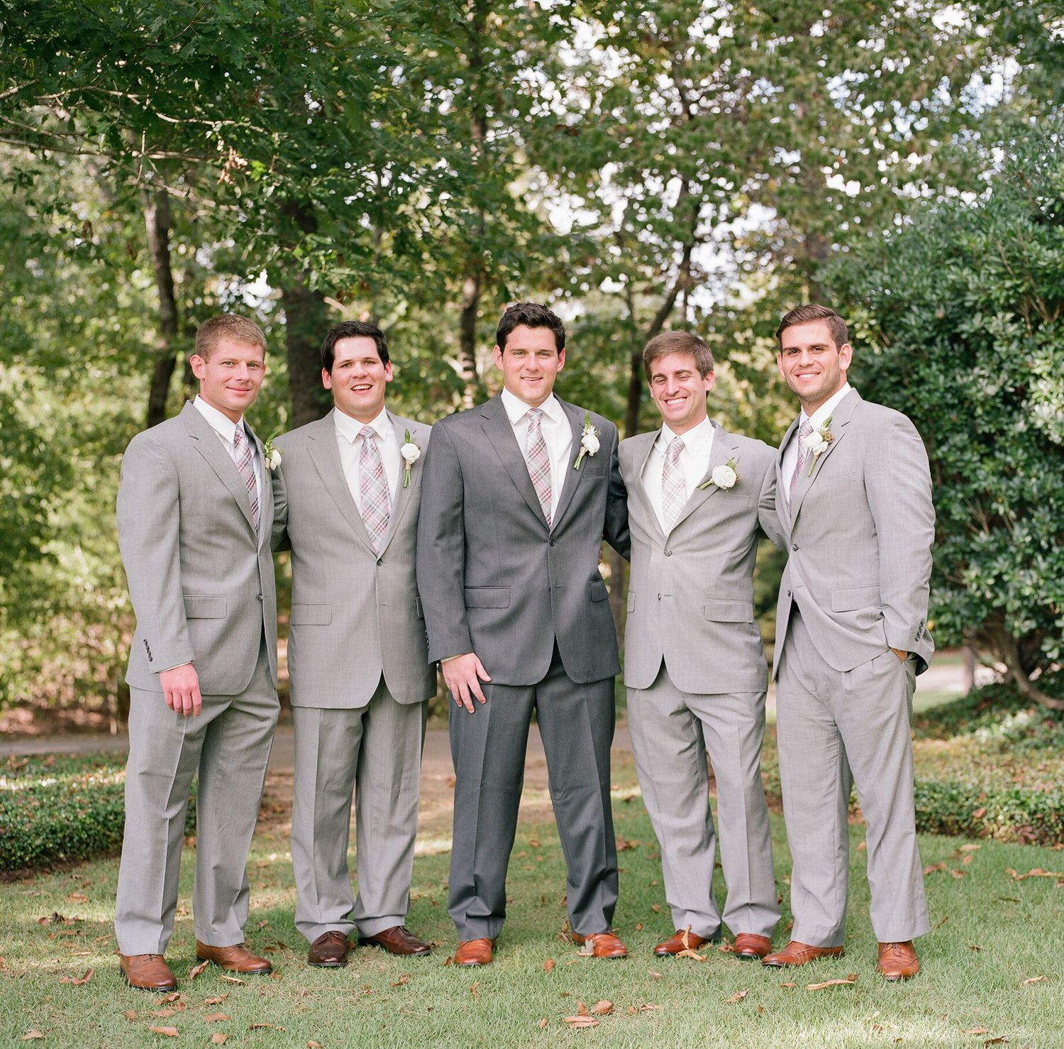 Groomsmen in matching gray suits stand in line for formal wedding photos.