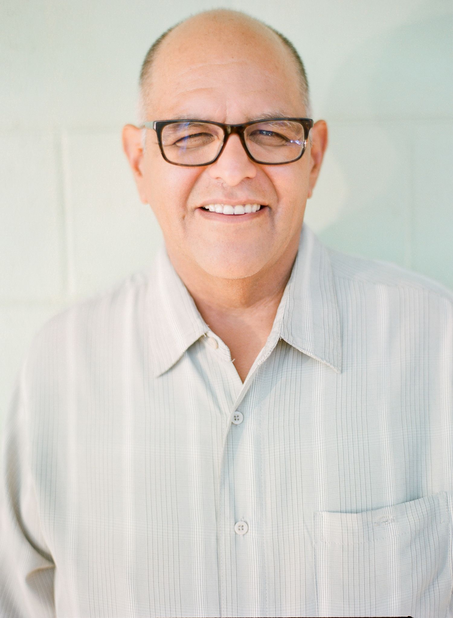 Portrait of someone wearing glasses and a white button-down shirt against a light blue background.