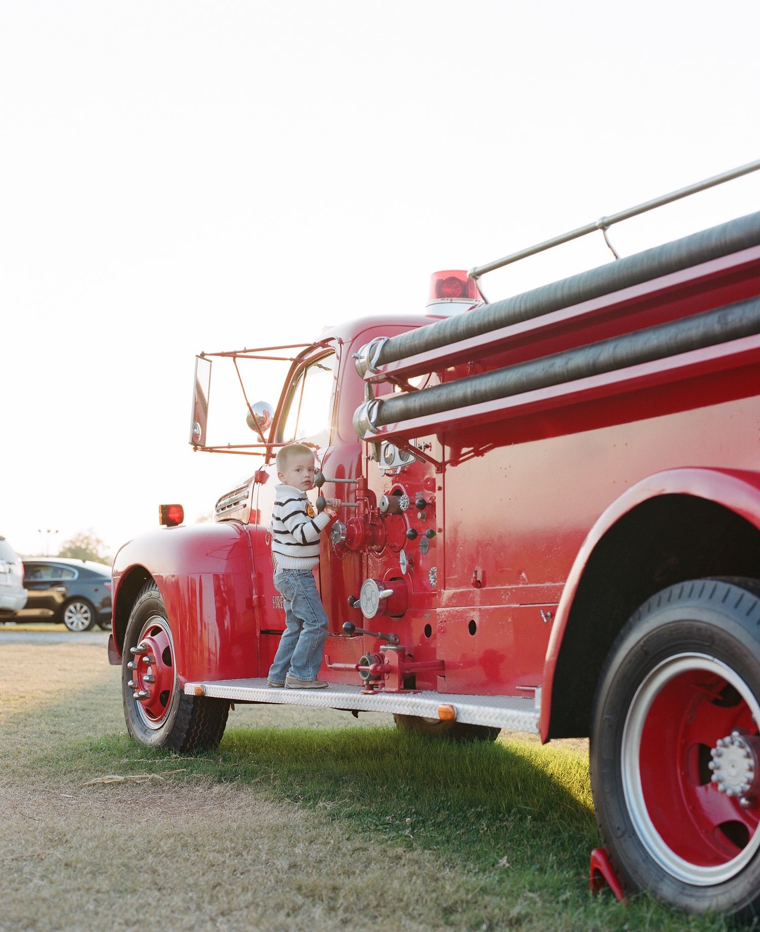 Classic red fire trucks lined up in a row on grassy ground.