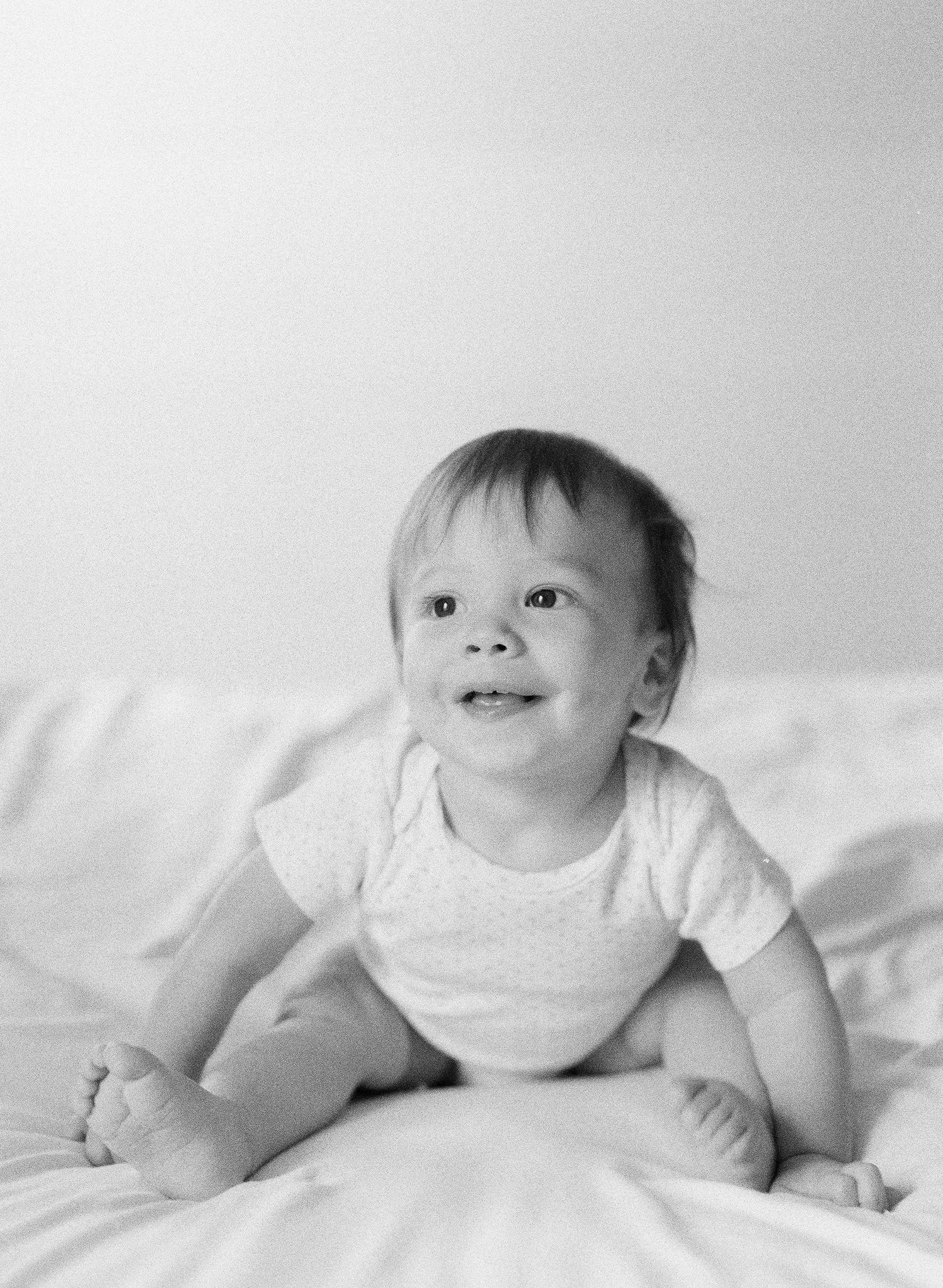 Black and white series of baby crawling on white bedding.