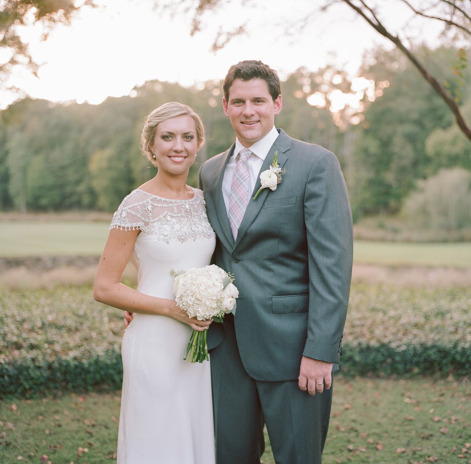 Wedding couple poses together in formal attire during outdoor sunset photo session.