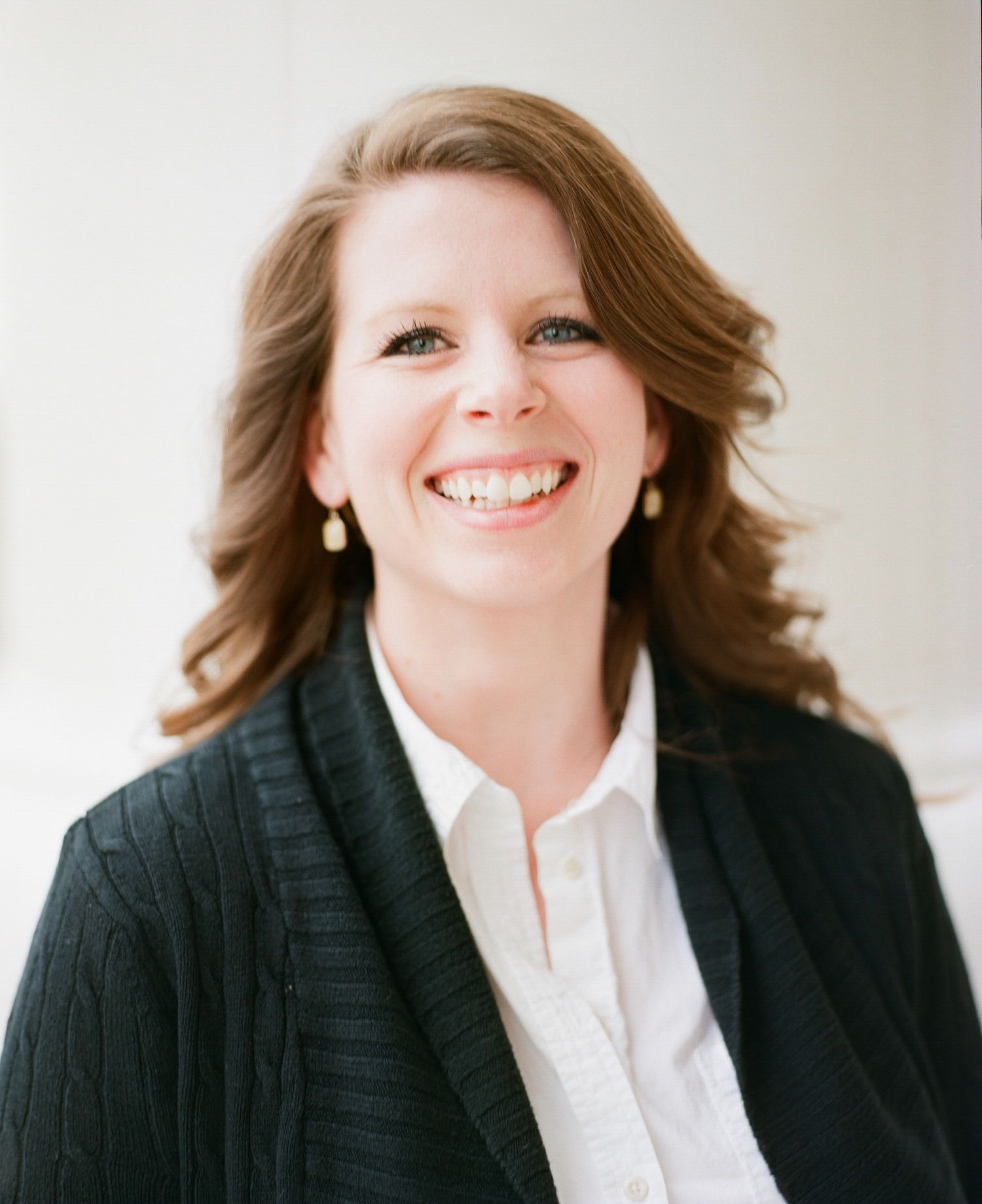 Professional headshots showing warm smiles and business attire against a light background.