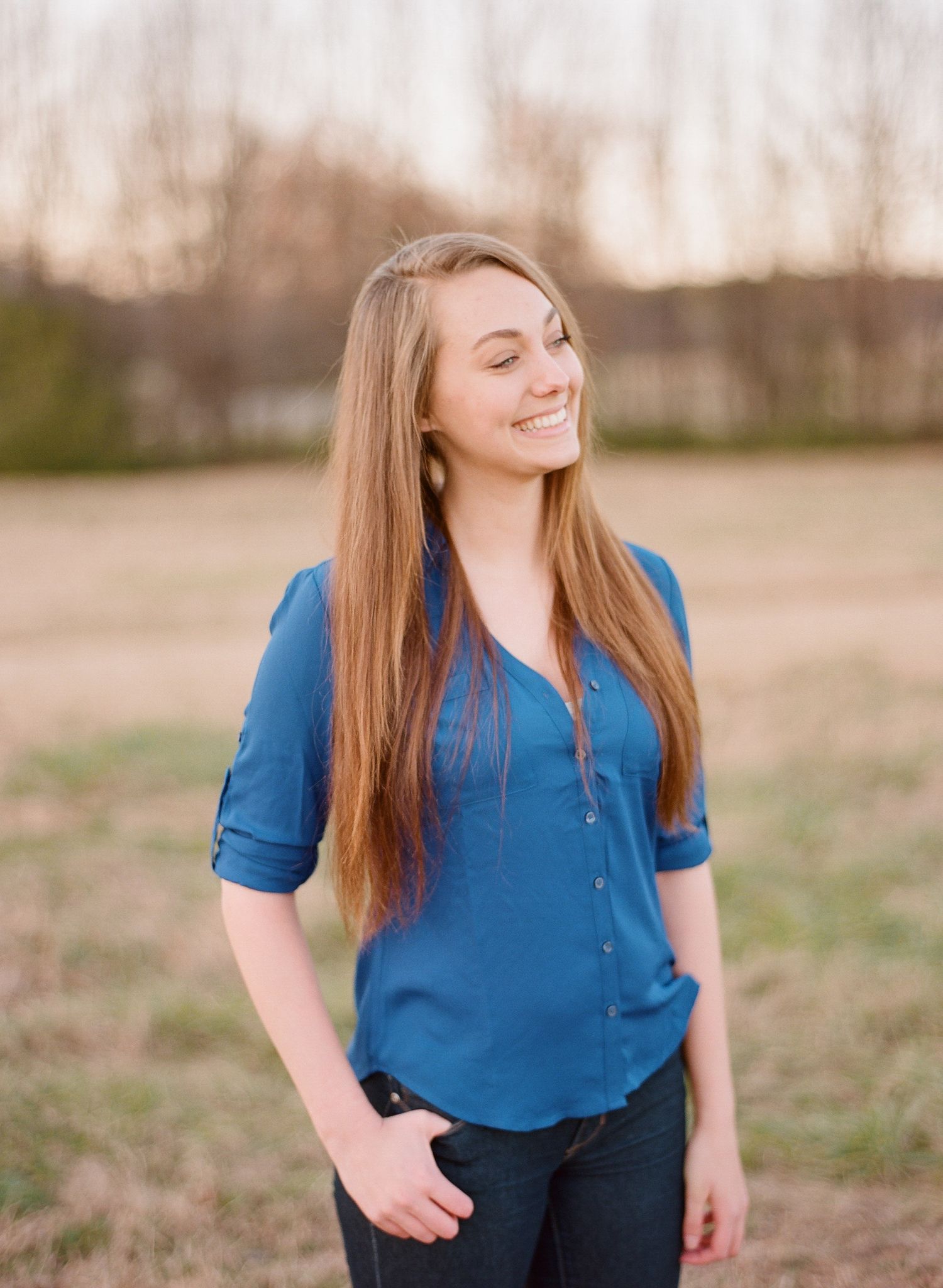 Portrait series of woman in blue top posing outdoors at golden hour.