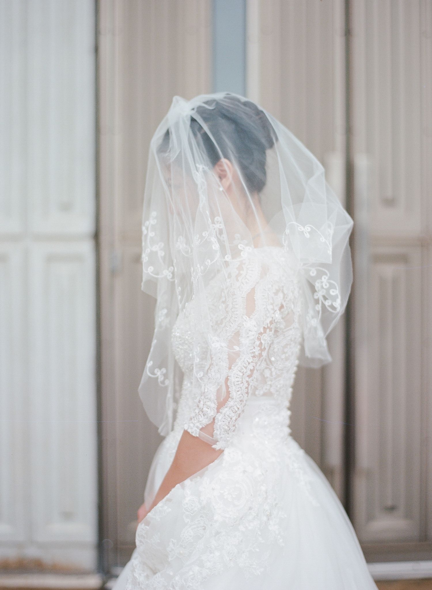 Back view of an elegant white wedding dress with sheer lace details.
