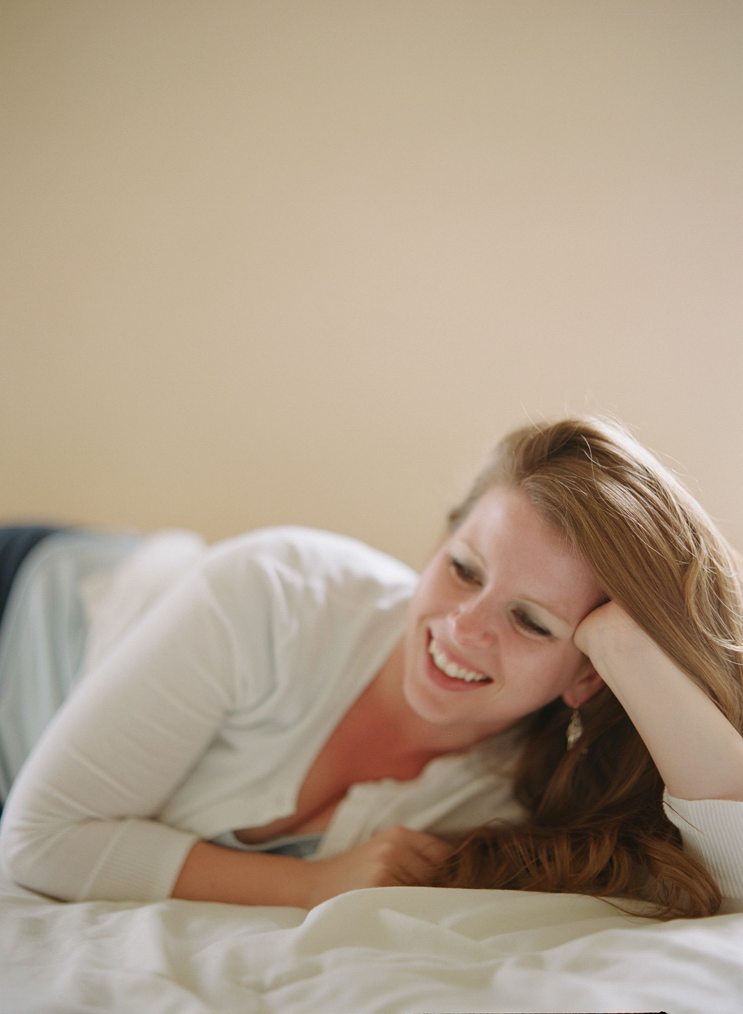 Natural light portrait capturing relaxed moments on white bedding.