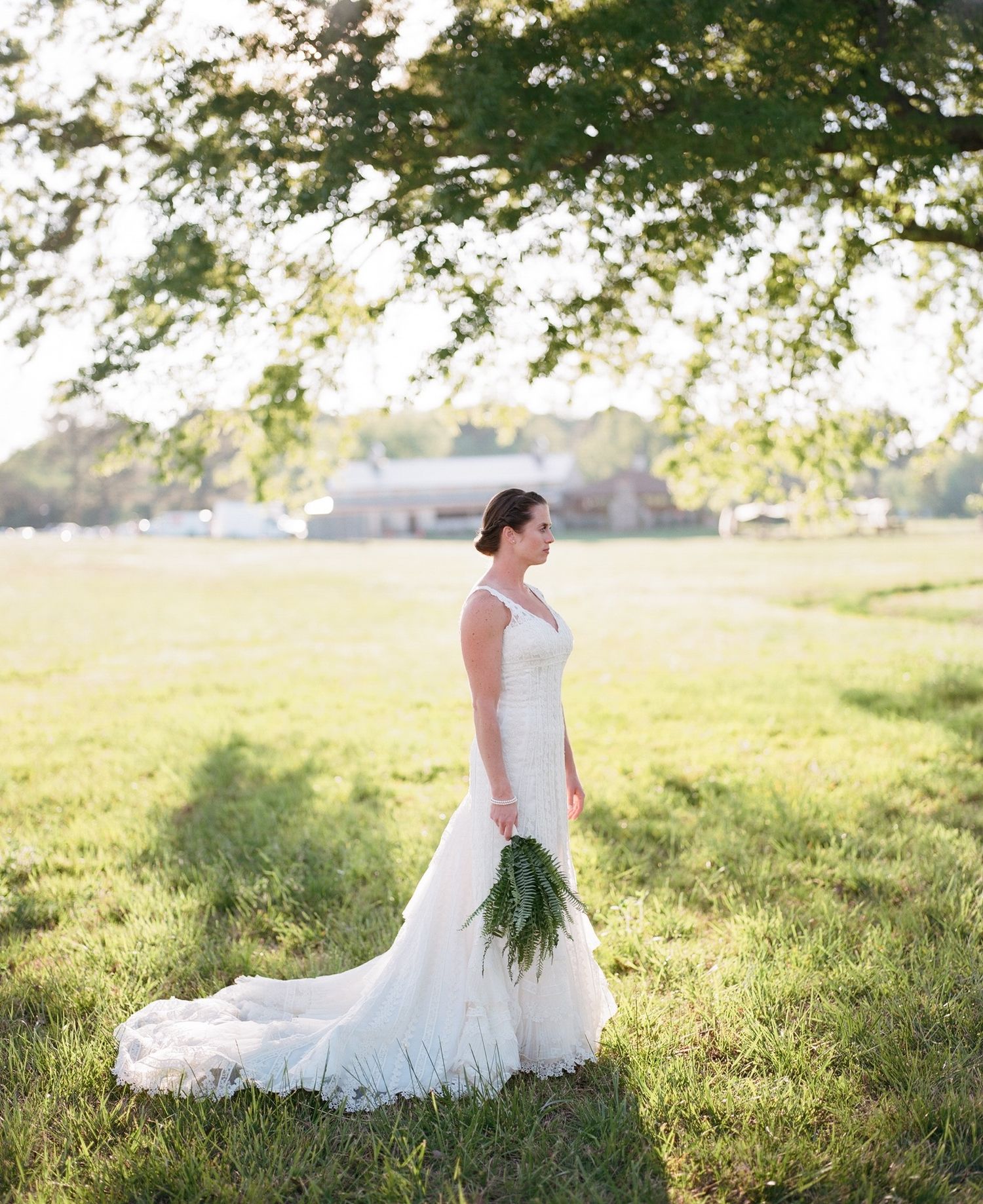 White wedding dress flowing in sunlit meadow during golden hour.