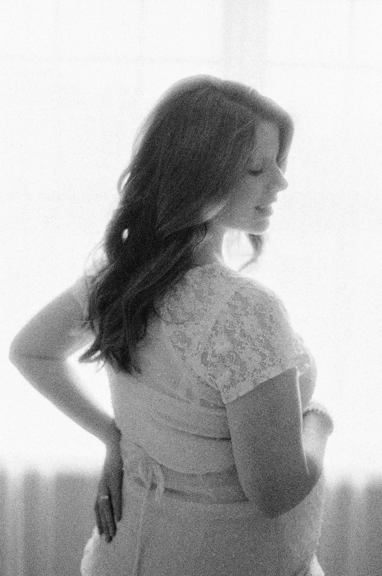 Artistic black and white boudoir portrait with lace details and window lighting.