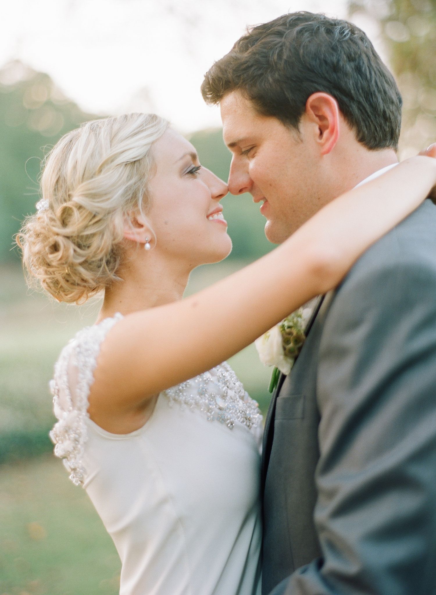 Romantic wedding couple embracing in an outdoor setting with soft natural lighting.