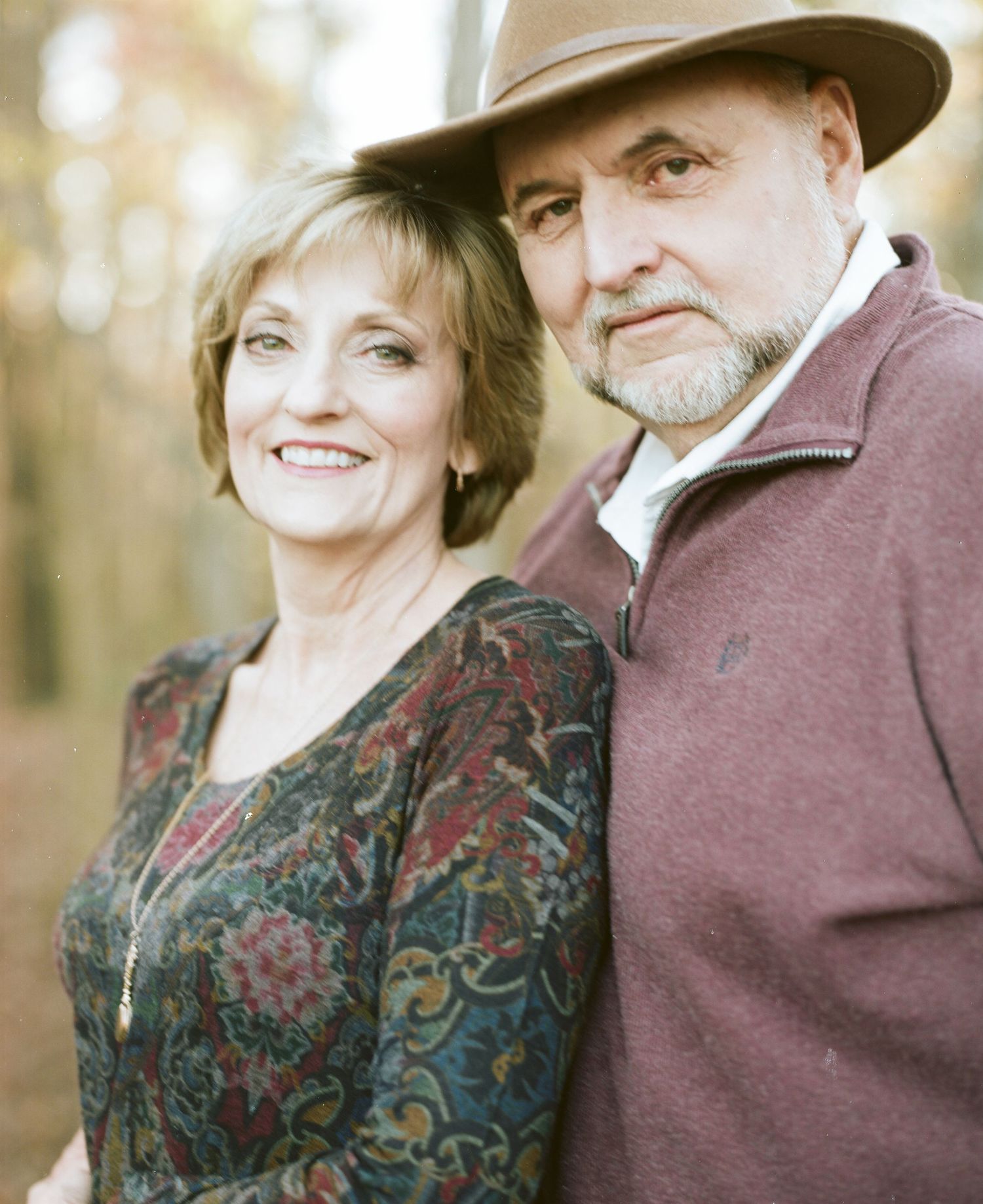 Mature couple in formal attire posing together outdoors.