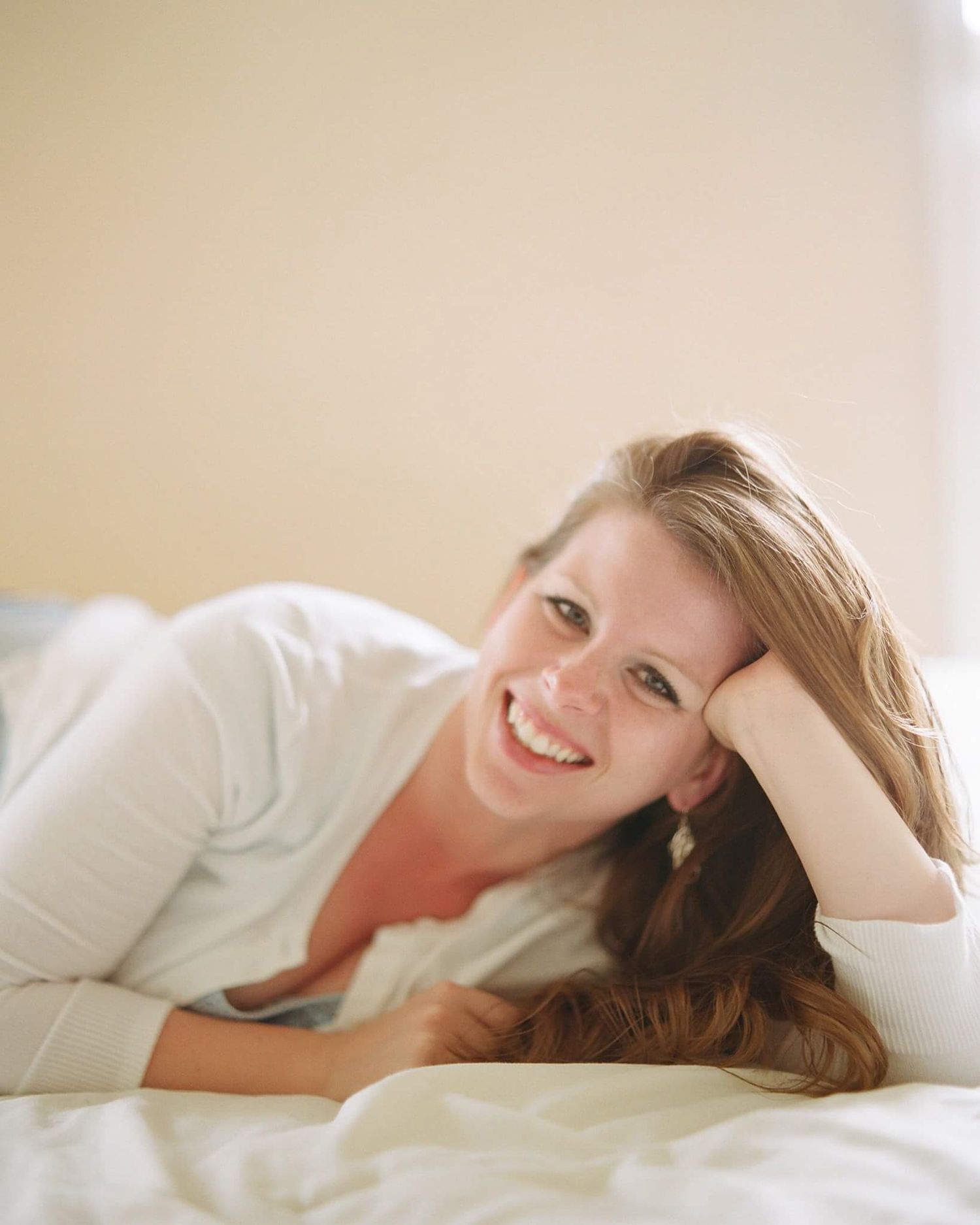 Lifestyle photos of woman relaxing on white bedding in casual attire.