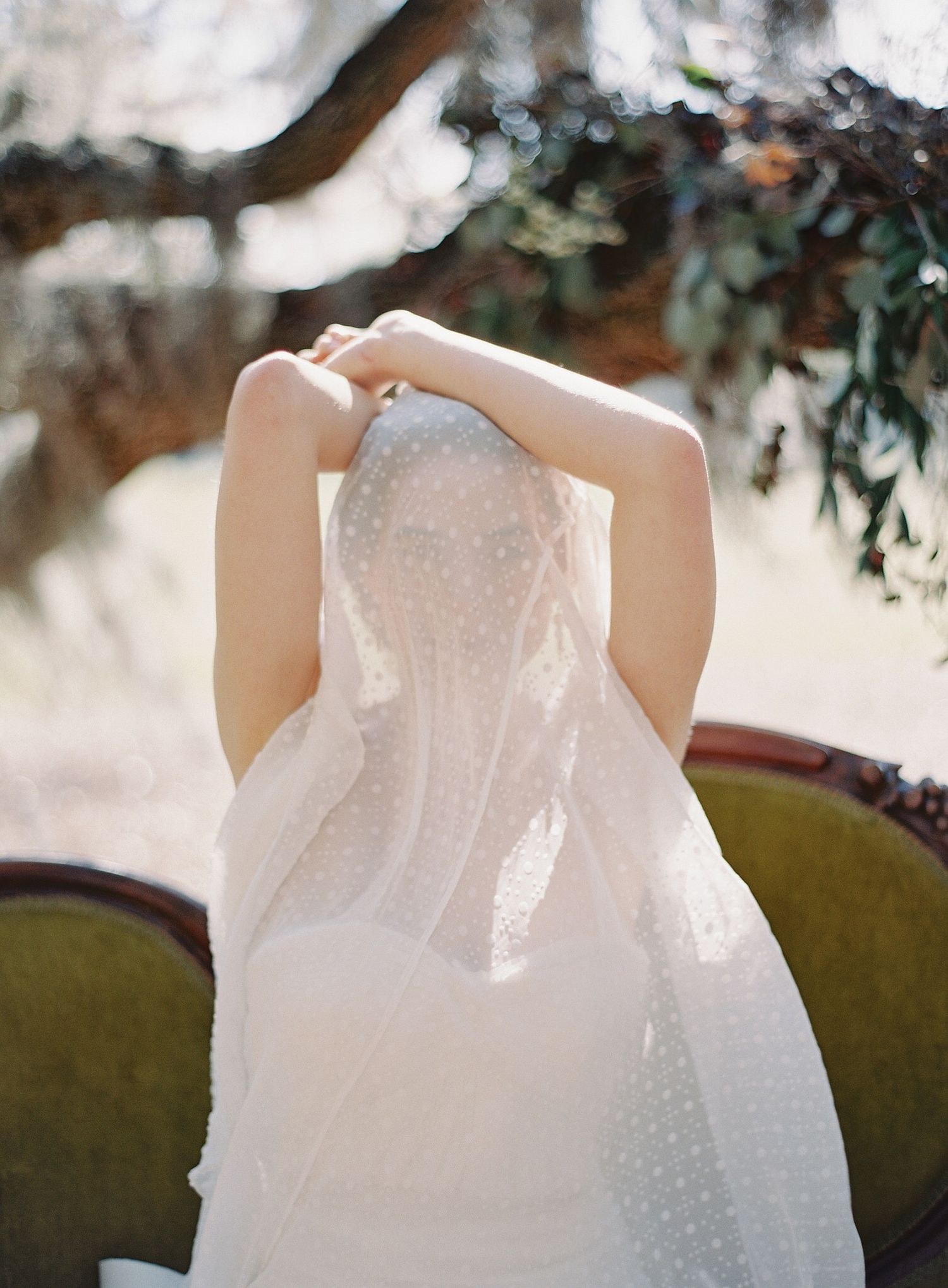 Detail shots of a white polka dot wedding dress hanging against a vintage green couch.