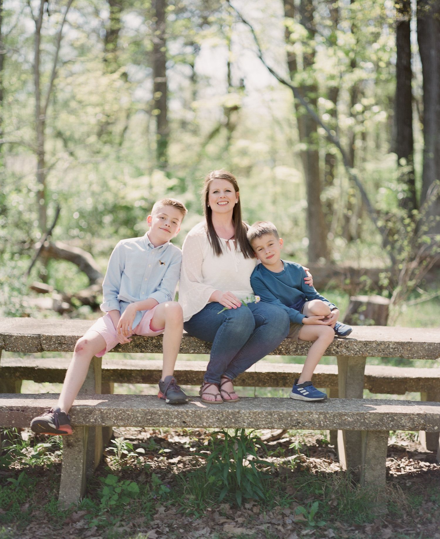 Family relaxing together on a wooden fence in a peaceful forest setting.