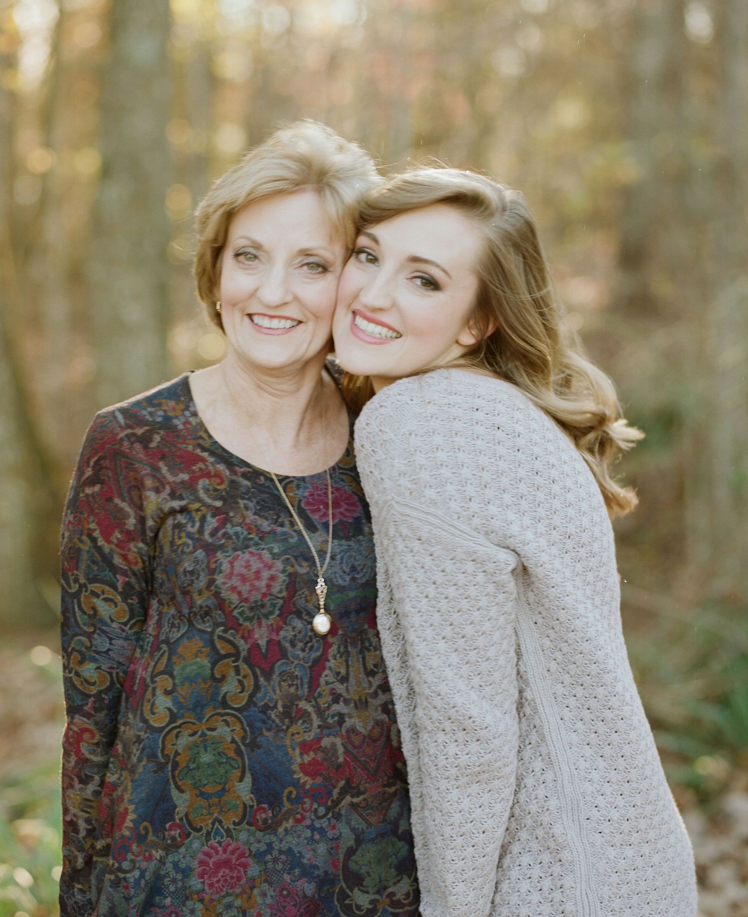 Mother and daughter sharing a joyful moment together in a forest setting.