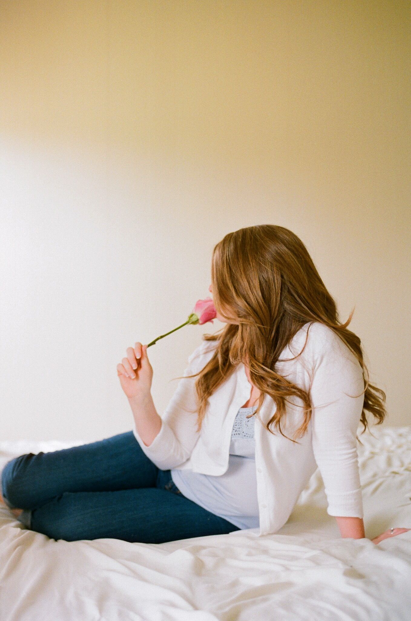 A person in white lounges on a bed in various relaxed poses against a neutral background.