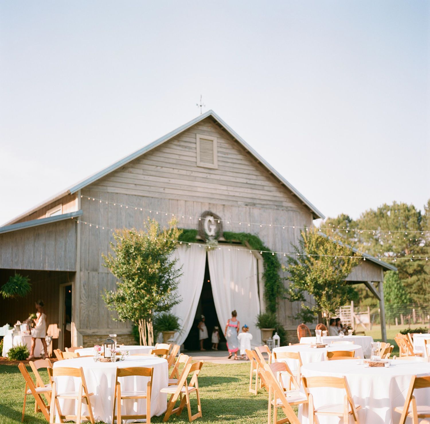 Rustic barn wedding reception setup with tables and chairs outdoors.
