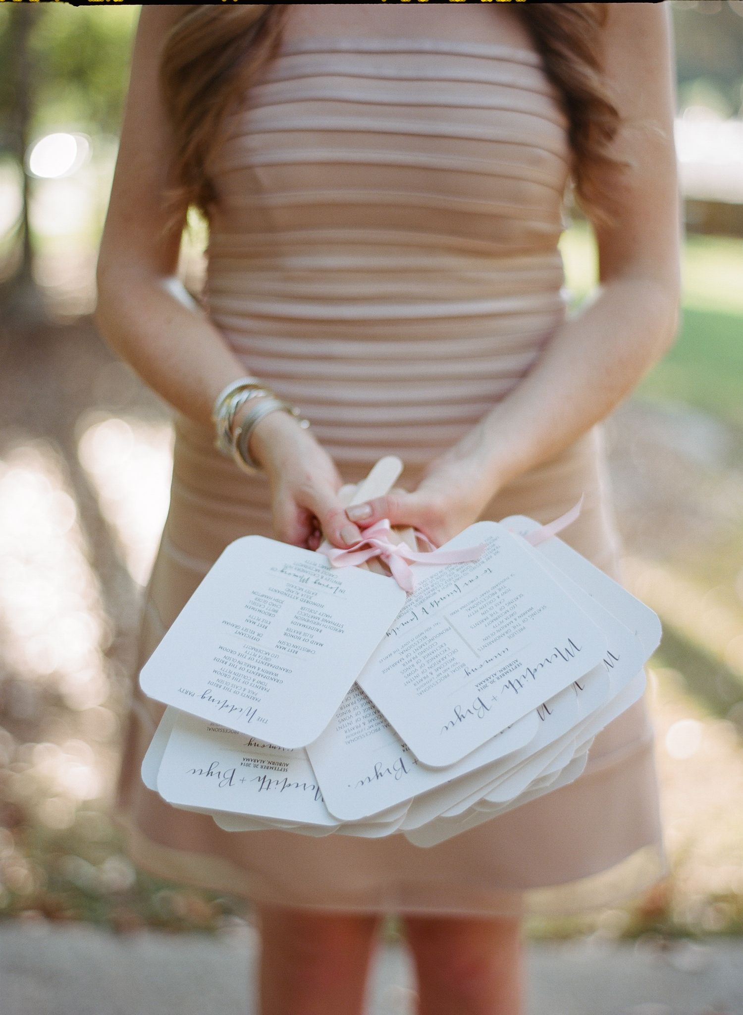 White paper cards or notes being held in hands against a light colored dress background.