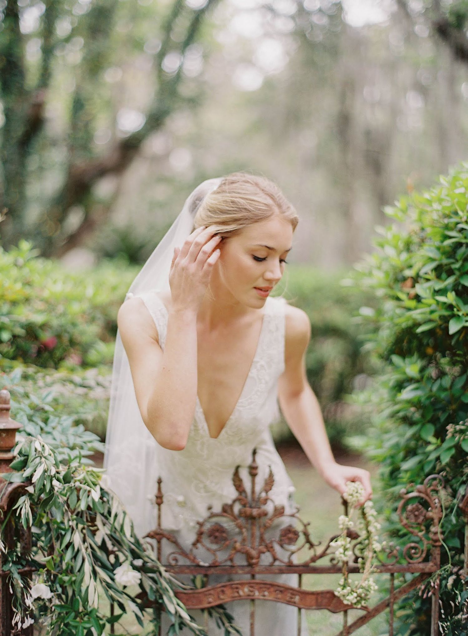 Bride in white dress exploring a lush garden setting with ornate decorative elements.