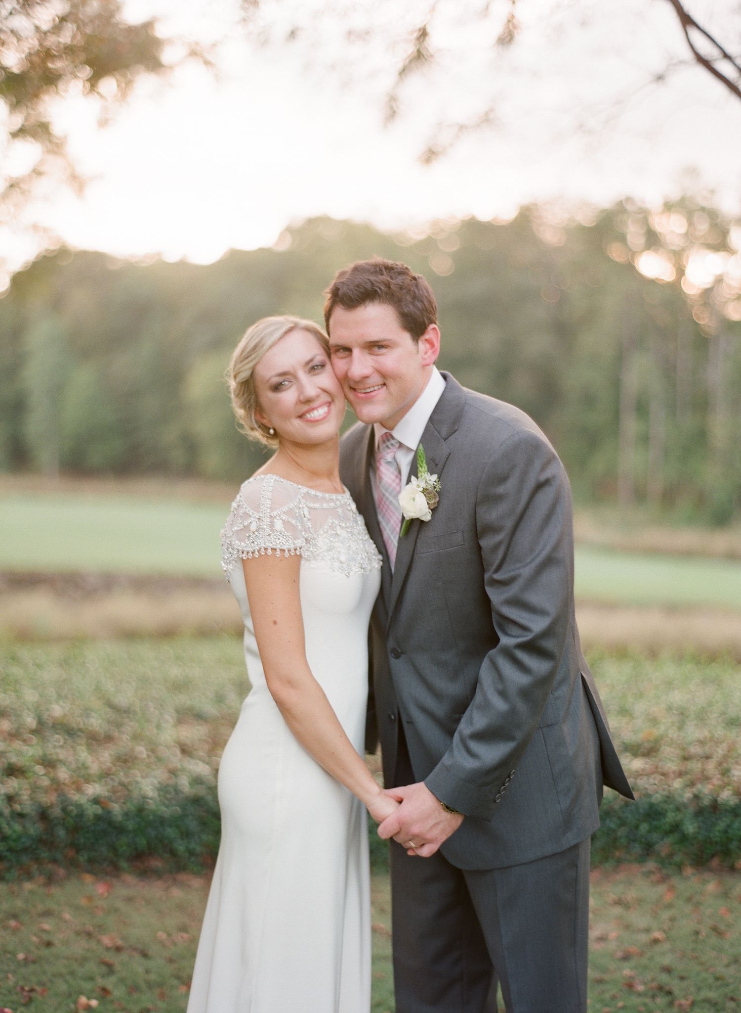 Romantic wedding couple embracing in a sunlit outdoor garden setting at sunset.