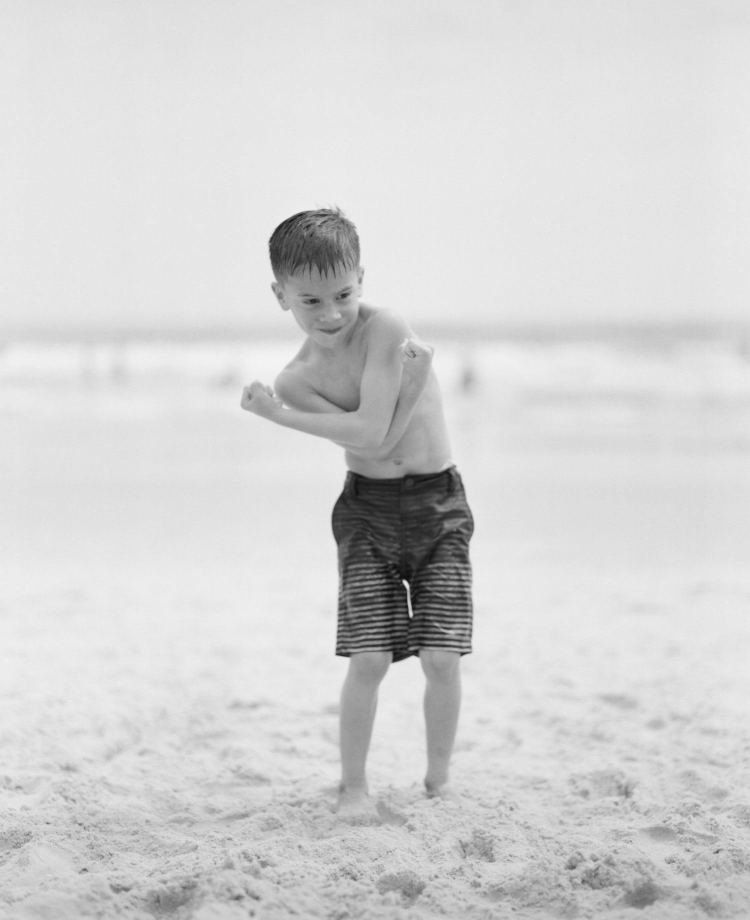 Child playing in white sand at the beach in black and white.