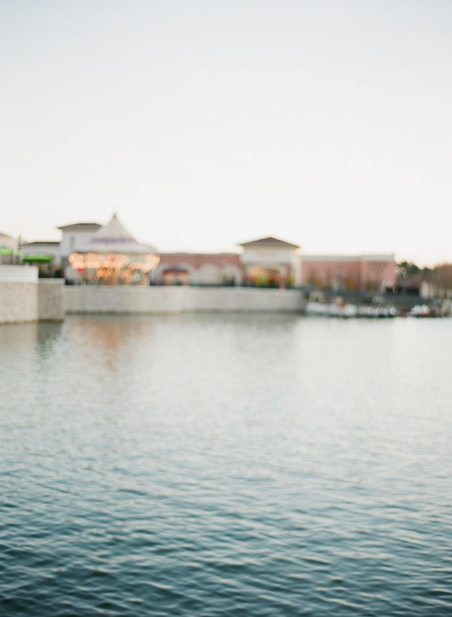Calm waterfront scene with buildings visible in the distance across tranquil blue water.