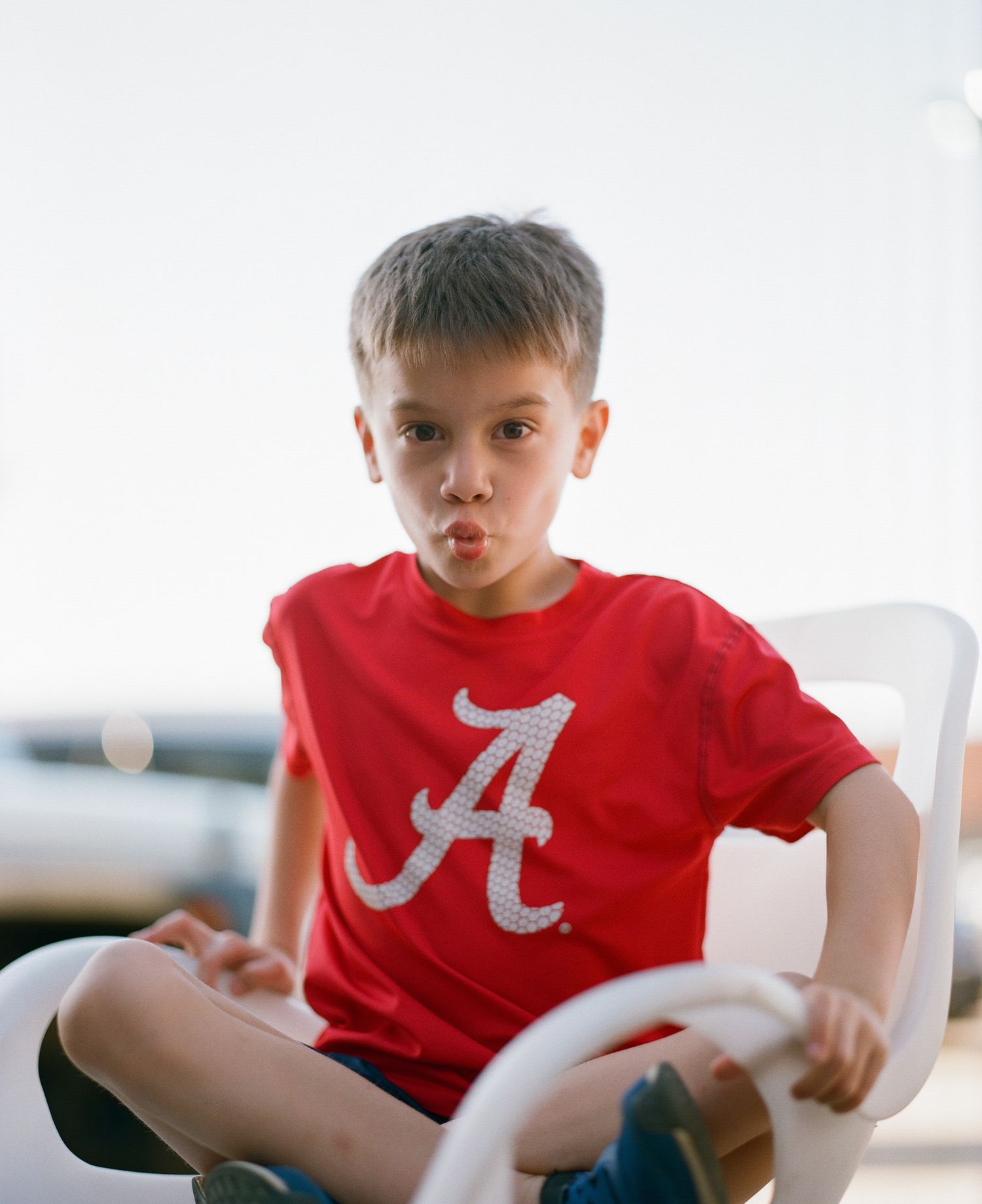 Young child wearing a red Alabama Crimson Tide t-shirt sitting indoors.