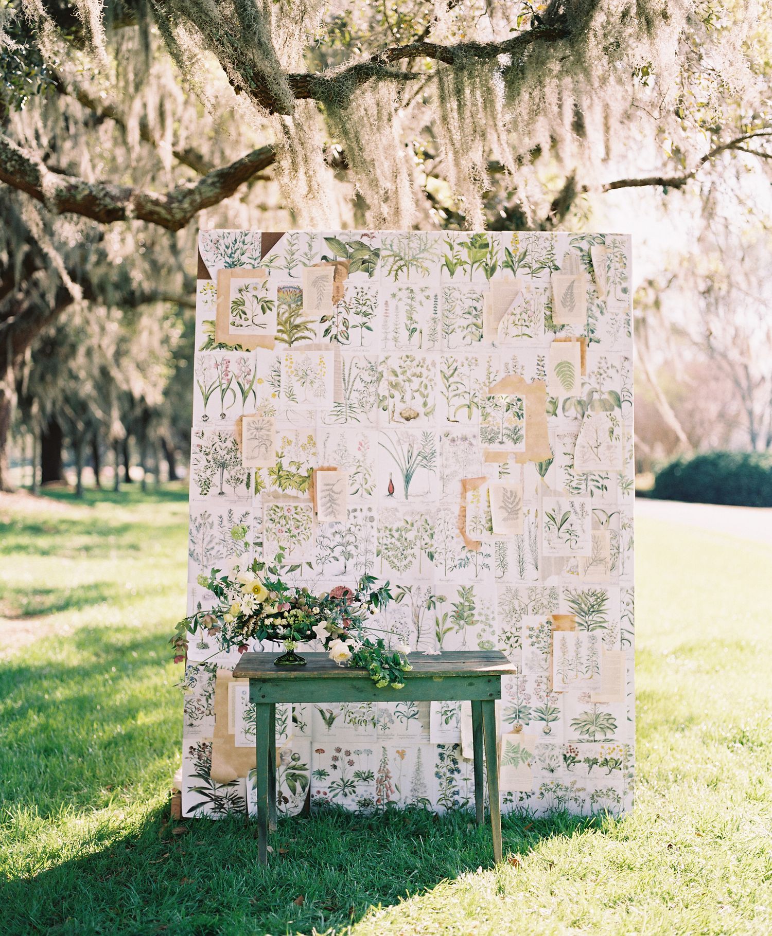 Decorative hanging glass panels create an ethereal outdoor display under moss-draped trees.