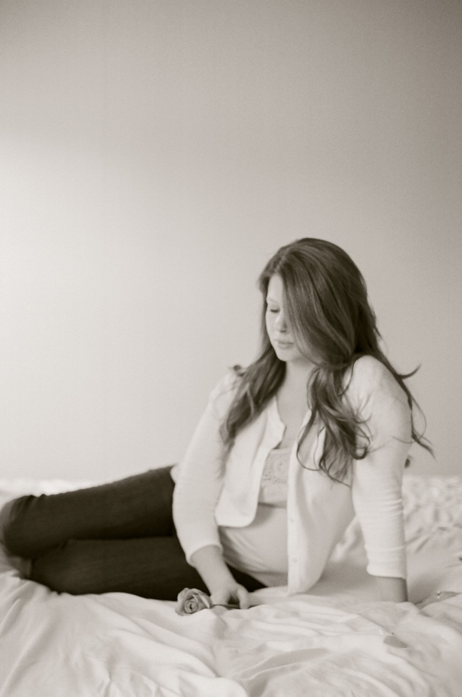 Black and white boudoir photo series showing relaxed poses on white bedding.