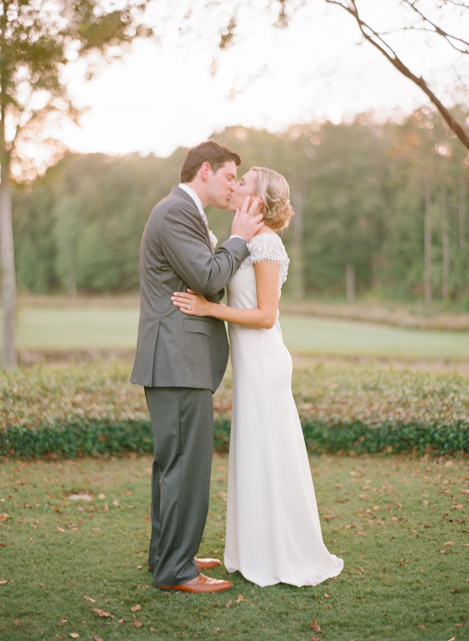 Wedding couple embraces on a grassy lawn during their outdoor photo session.