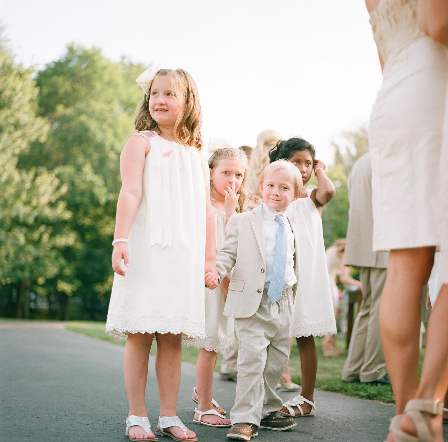 Close-up view of children's feet and legs at an outdoor wedding ceremony.