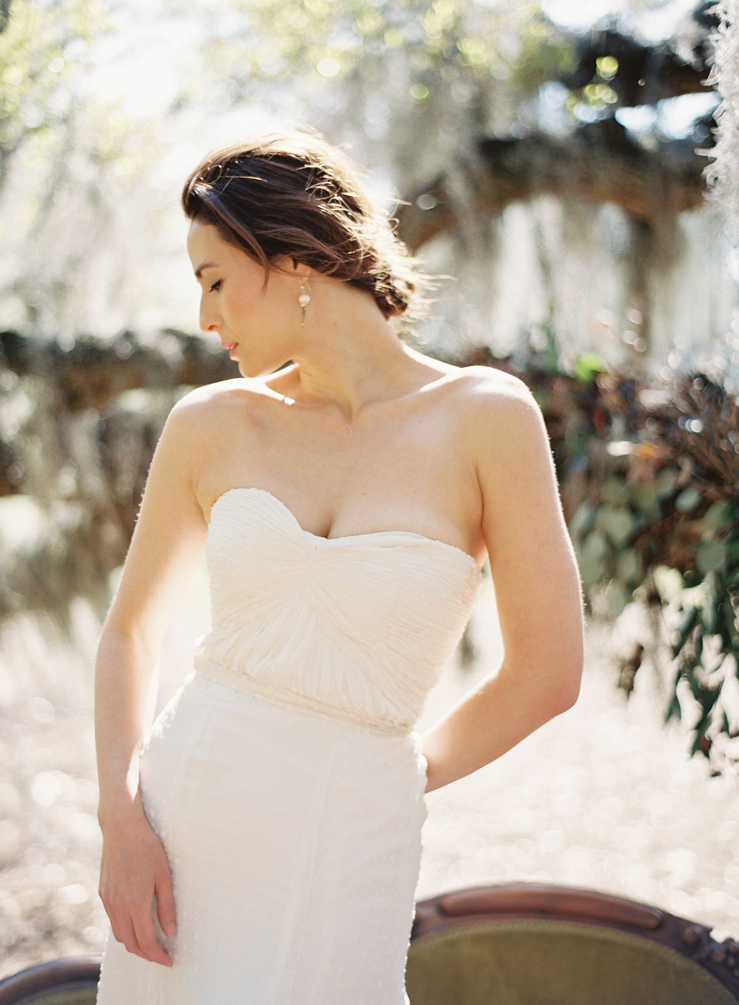 Elegant white wedding dress detail shot with soft natural lighting and Spanish moss in background.