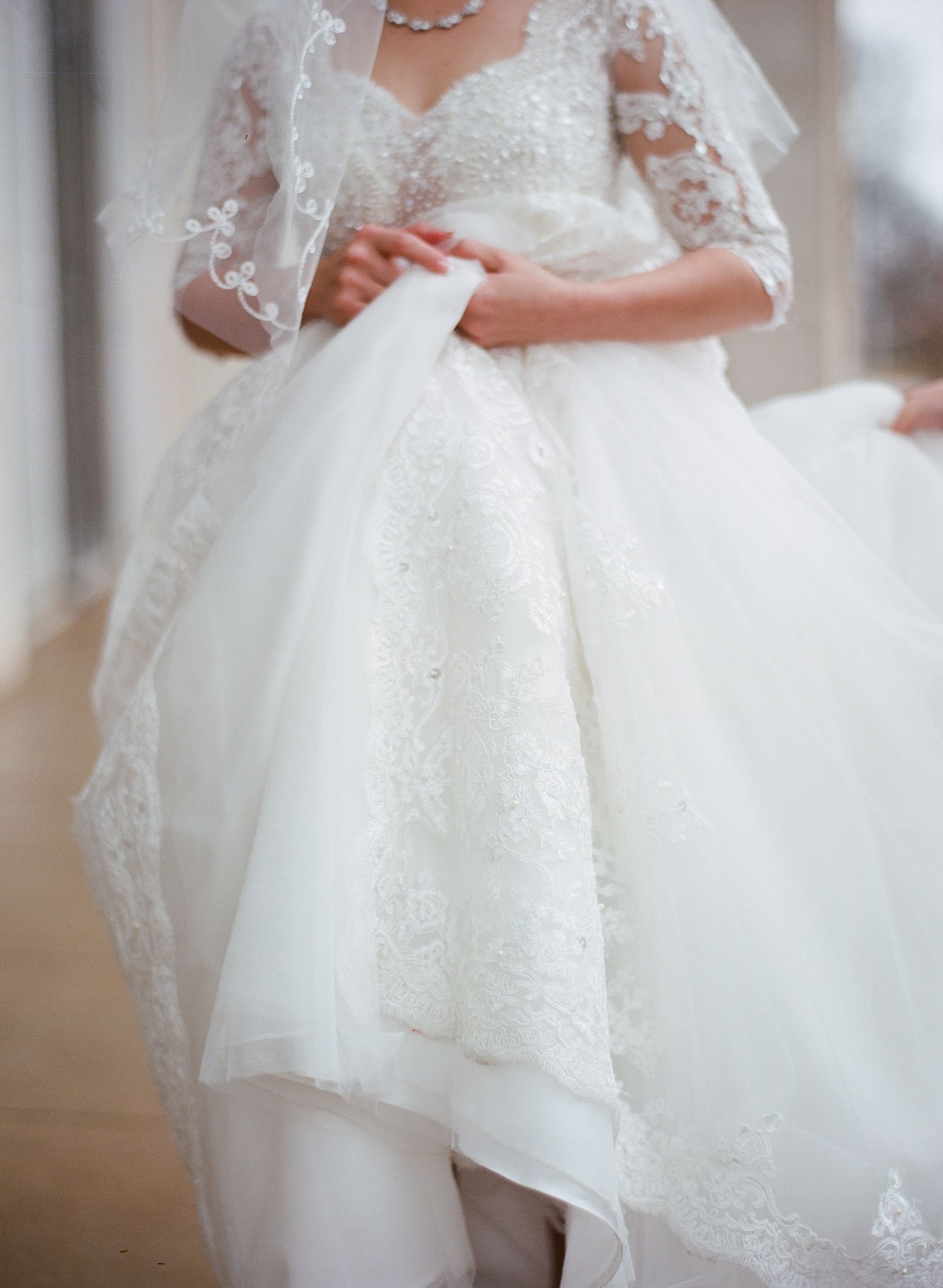Close-up details of a white lace wedding dress with delicate beading and tulle.