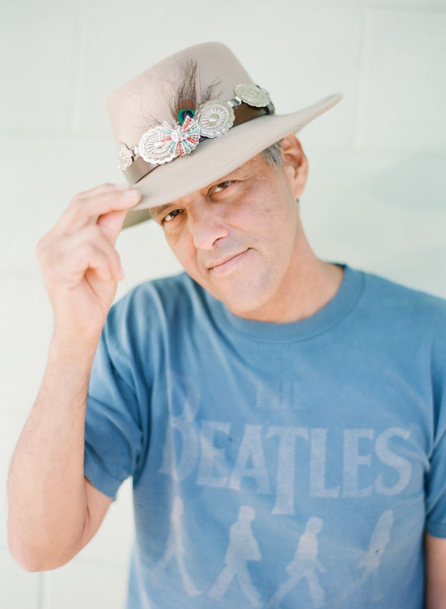 Person wearing a Beatles t-shirt and beige cowboy hat poses in a sequence.