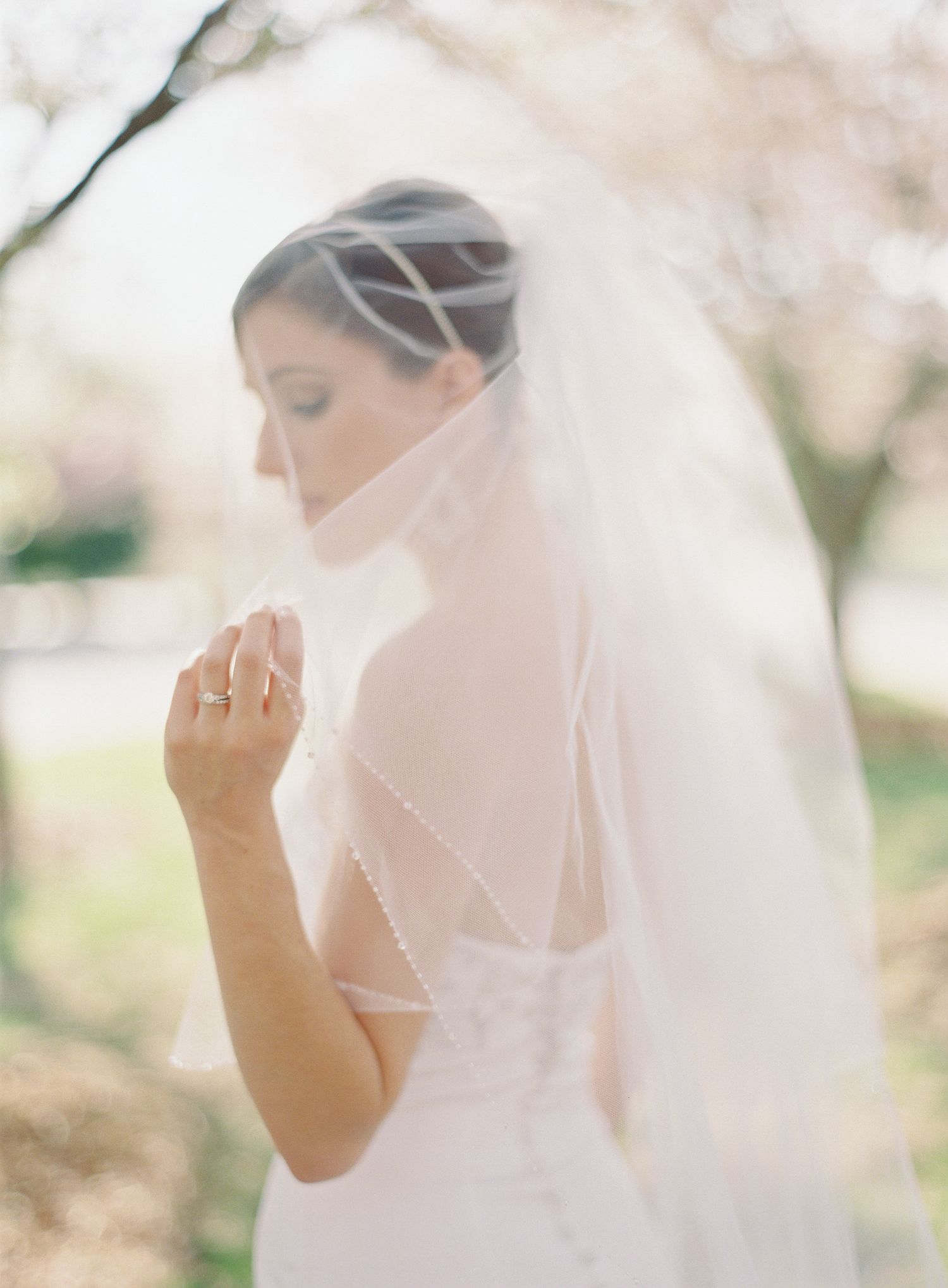 Ethereal bridal portrait through sheer veil in soft natural light.
