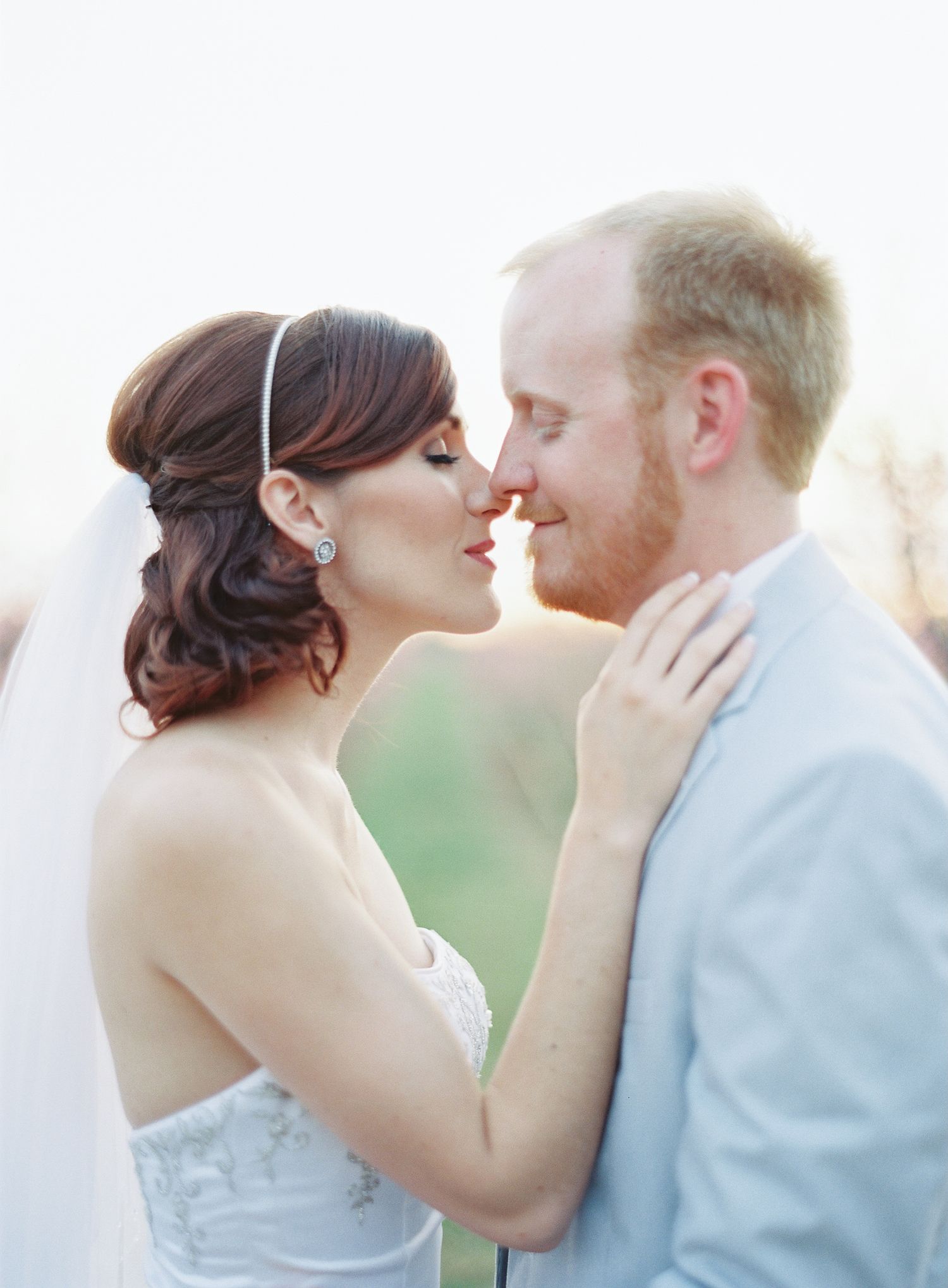 Romantic couple in wedding attire shares intimate moments at sunset.