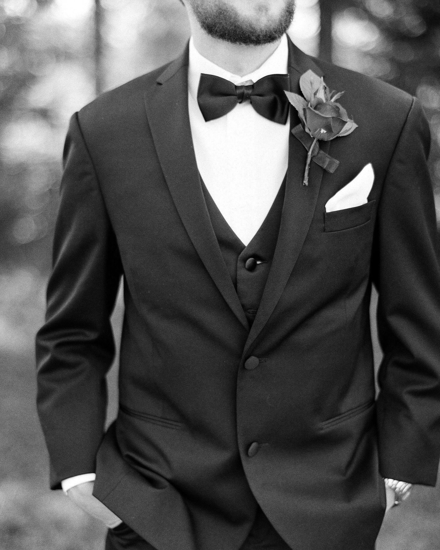 Close-up of formal black tuxedos with bow ties and boutonnieres.