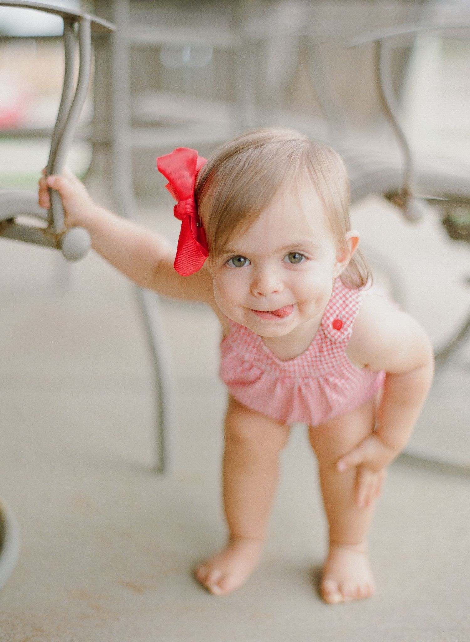 Baby in pink gingham outfit playing on a light colored floor.