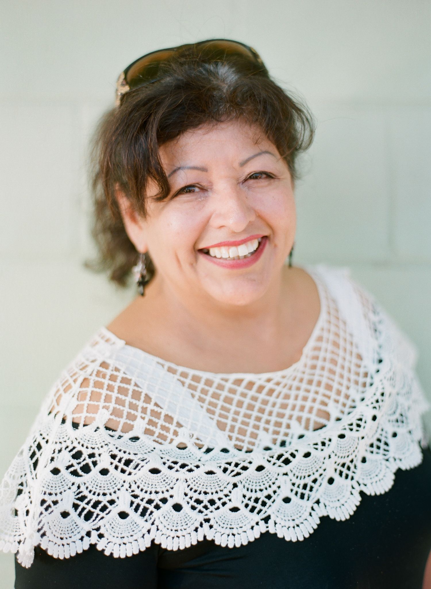 Portrait featuring a delicate white lace collar against a dark top with a light background.
