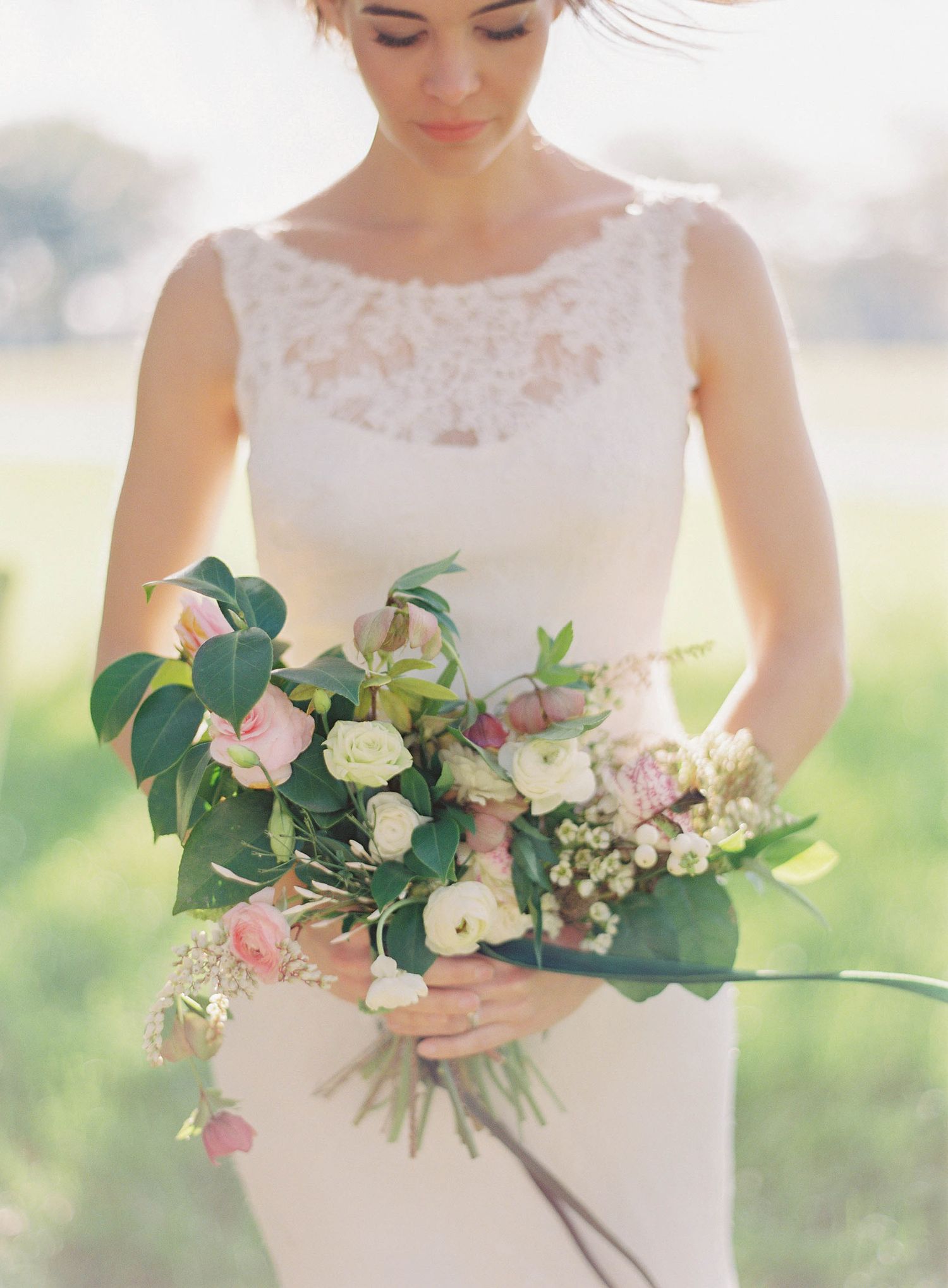 Delicate bridal bouquet with pink and white flowers and green foliage.