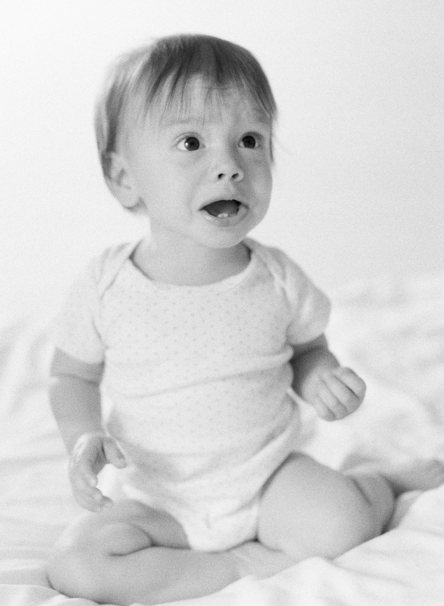 Black and white portraits of infant on white sheets.