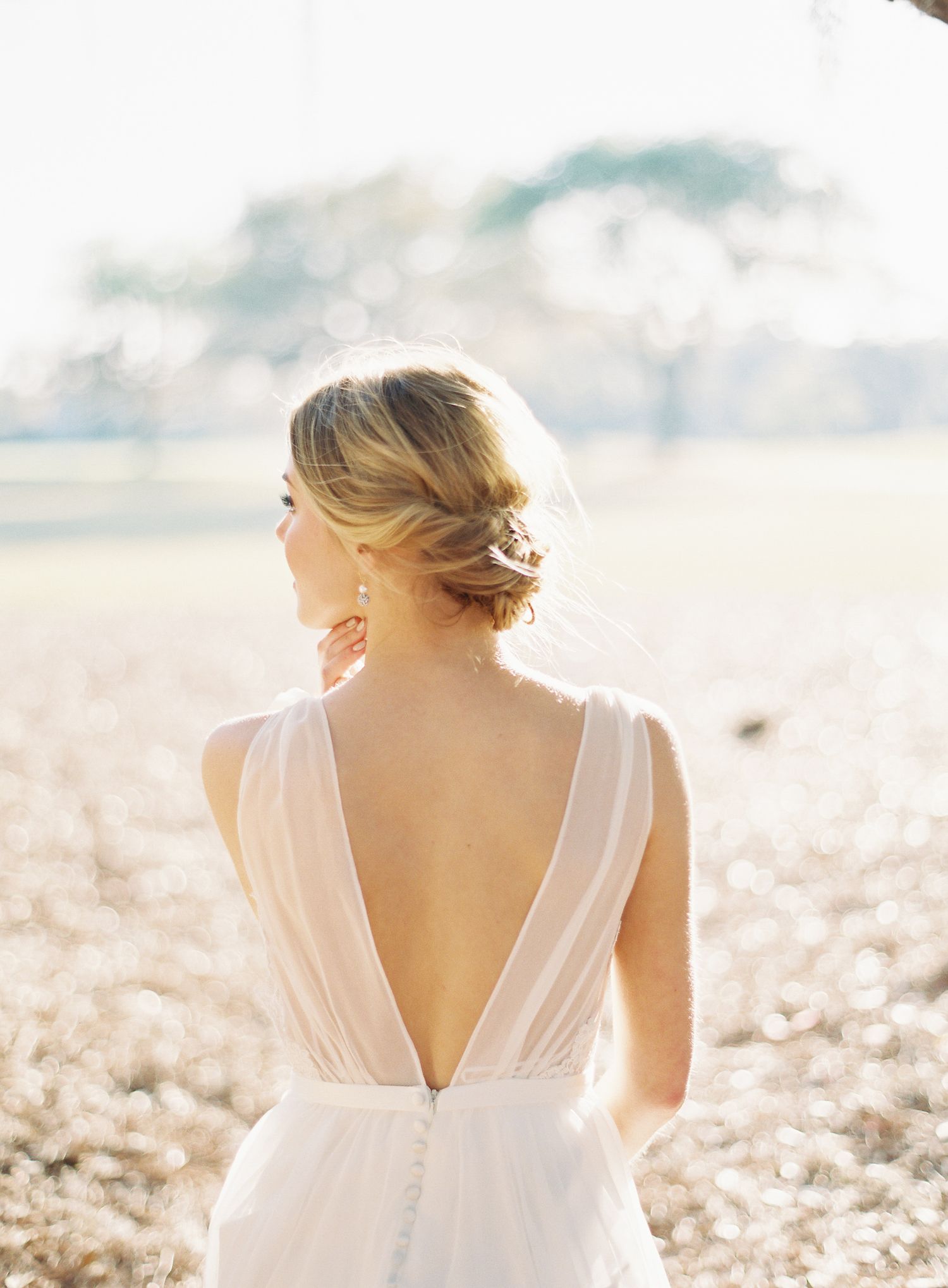 Sunlit bridal portrait showing the back details of a white wedding dress.