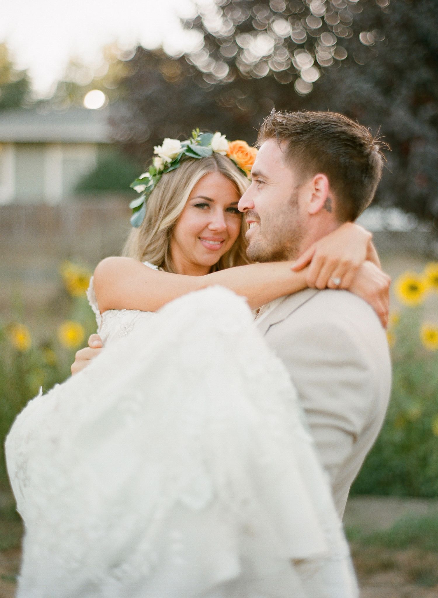 Wedding couple embracing in a sunlit field with sunflowers in the background.
