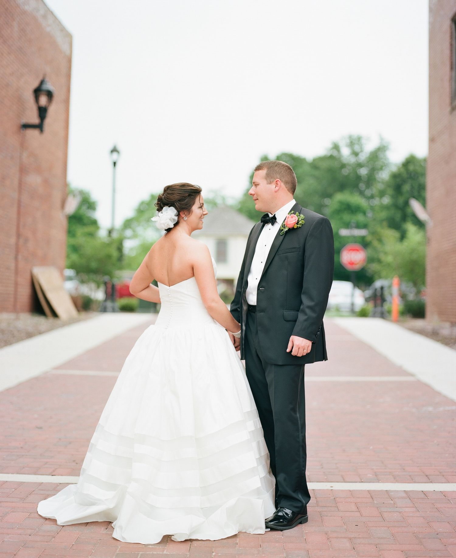 Wedding couple walking along a brick pathway with flowing white dress.