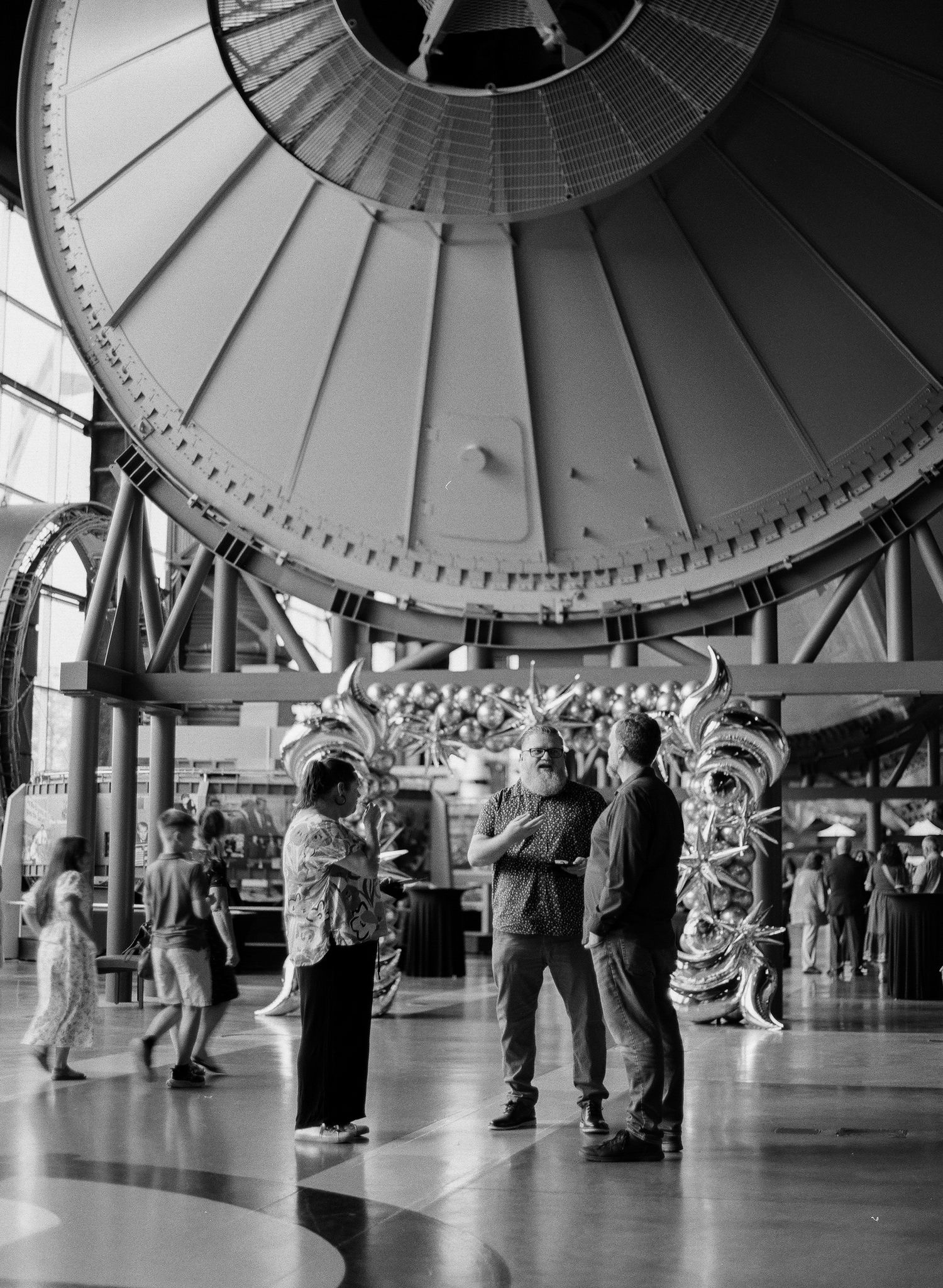 Black and white photo of visitors gathered beneath a large domed structure at an aviation museum exhibit.